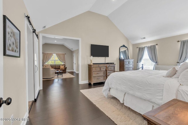 bedroom featuring visible vents, dark wood-style flooring, baseboards, a barn door, and vaulted ceiling