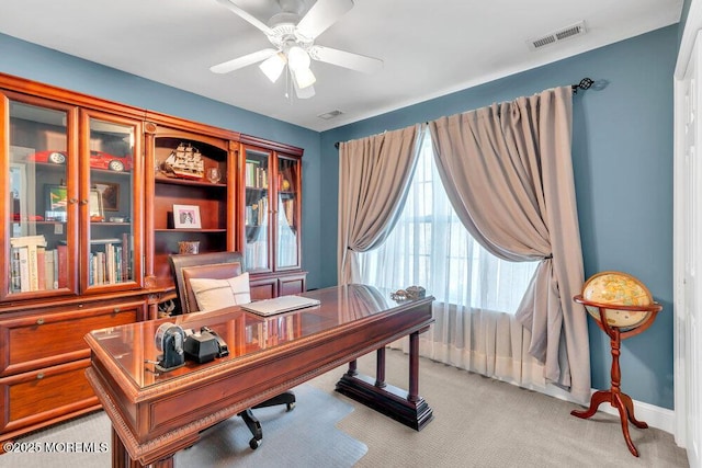 home office with baseboards, light carpet, a ceiling fan, and visible vents