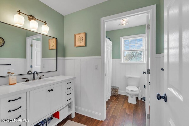 bathroom featuring vanity, wainscoting, toilet, and wood finished floors