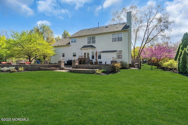 rear view of property featuring a yard, a chimney, and a patio area