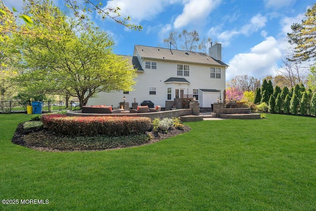 rear view of house with fence, a patio, a chimney, an attached garage, and a yard