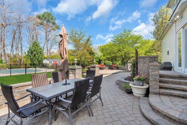 view of patio with fence, outdoor dining area, and a fenced in pool