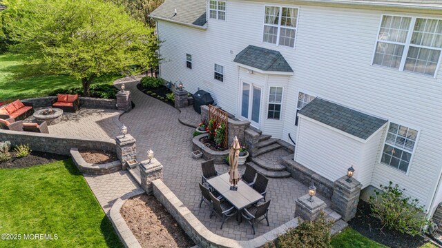 rear view of house featuring a shingled roof, a patio area, and an outdoor fire pit