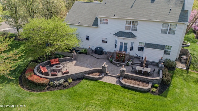 rear view of property with a lawn, a patio, and a fire pit