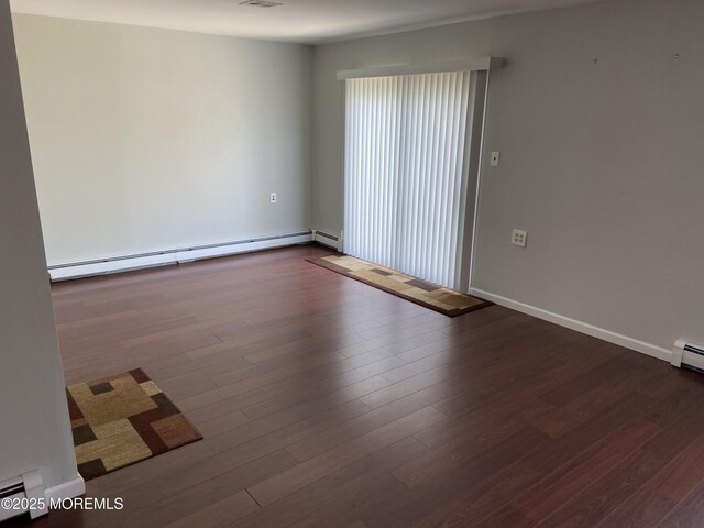 spare room with dark wood-style floors, baseboards, and a baseboard radiator