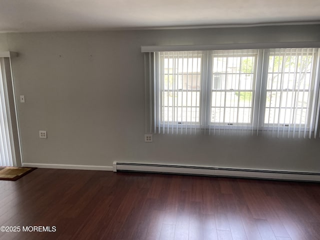 unfurnished room featuring dark wood-type flooring, baseboard heating, and baseboards