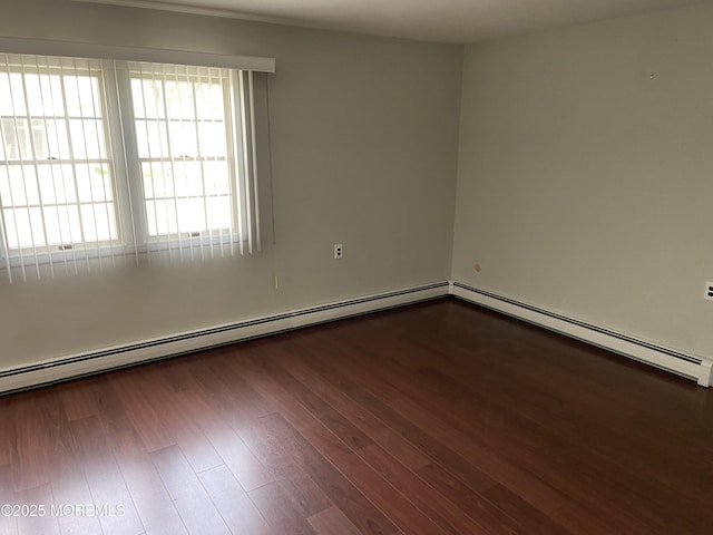 empty room with wood finished floors and baseboard heating