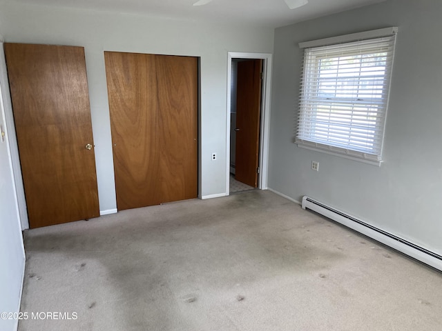 unfurnished bedroom with carpet flooring, baseboard heating, two closets, and baseboards
