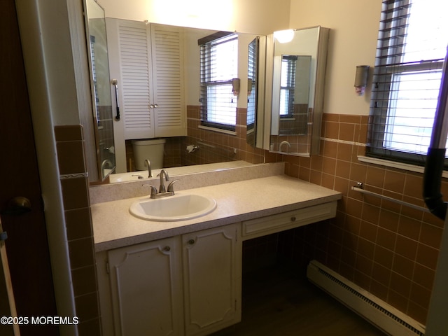 bathroom with tile walls, vanity, a wainscoted wall, and baseboard heating