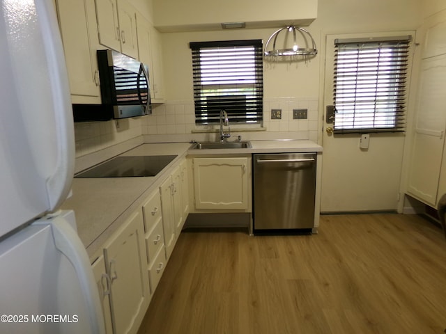 kitchen featuring backsplash, white cabinetry, stainless steel appliances, and a sink