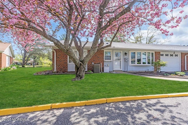 ranch-style house with central air condition unit, board and batten siding, brick siding, a front yard, and a garage
