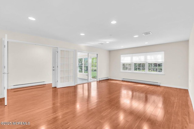unfurnished room featuring wood finished floors, visible vents, and a baseboard radiator