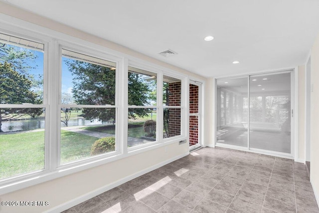 unfurnished sunroom with visible vents, baseboards, recessed lighting, and a water view