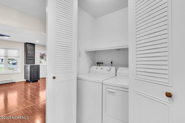 washroom with a baseboard heating unit, washing machine and clothes dryer, wood finished floors, and laundry area