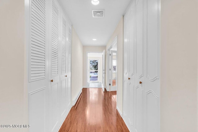 hall with baseboards, wood finished floors, visible vents, and recessed lighting