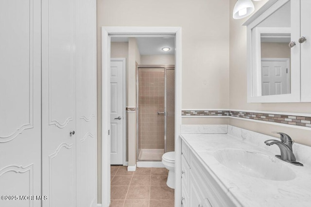 bathroom featuring tile patterned flooring, a shower stall, toilet, and vanity