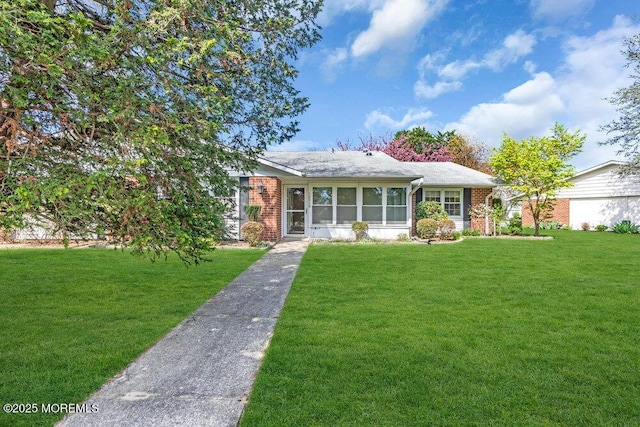 view of front of home featuring brick siding, a sunroom, and a front lawn
