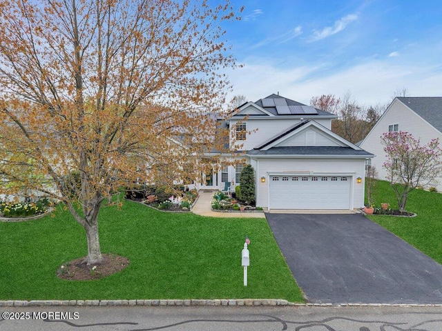 traditional-style home featuring roof mounted solar panels, a garage, driveway, and a front yard