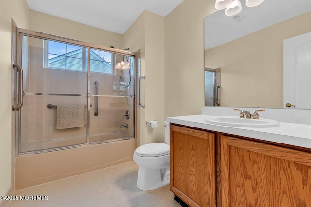 full bath with vanity, toilet, tile patterned floors, visible vents, and bath / shower combo with glass door