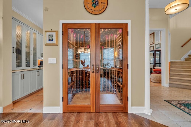 doorway featuring baseboards, light tile patterned floors, stairway, and french doors