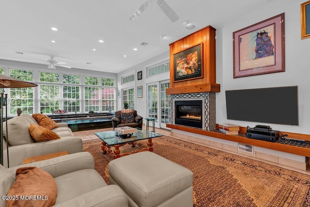 living area featuring a ceiling fan, recessed lighting, and a glass covered fireplace