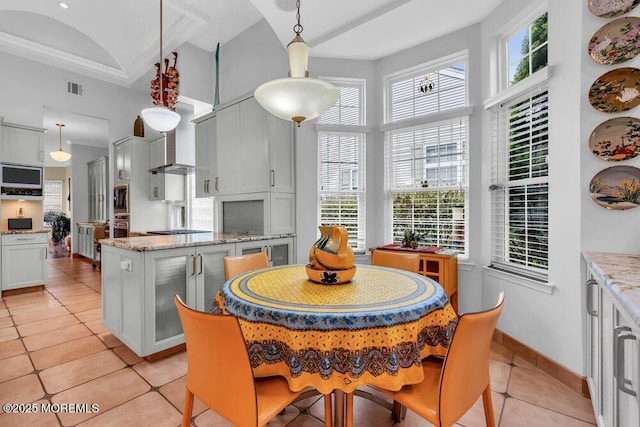 dining space featuring visible vents, a towering ceiling, and light tile patterned floors