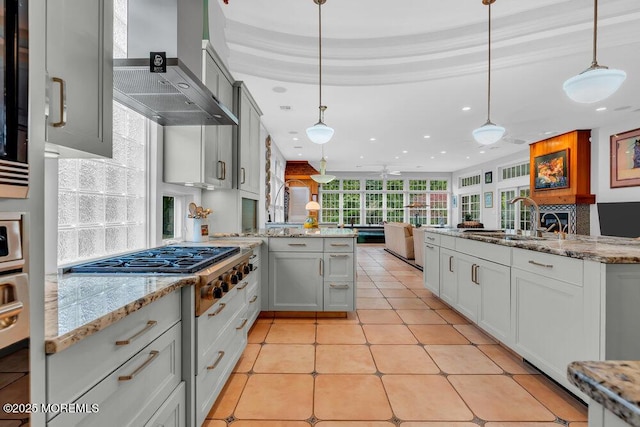 kitchen featuring recessed lighting, a sink, wall chimney exhaust hood, and a peninsula