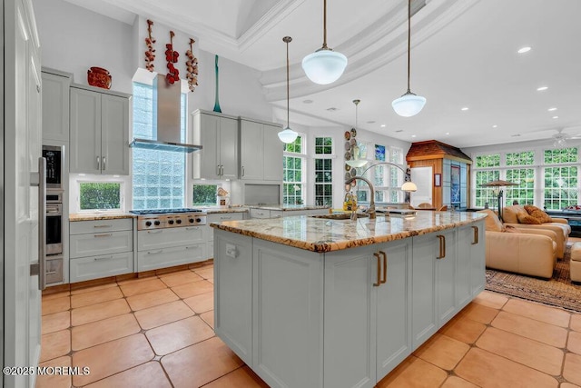 kitchen featuring appliances with stainless steel finishes, a sink, light tile patterned floors, open floor plan, and a wealth of natural light
