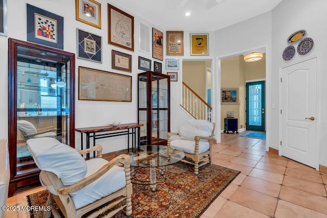 living area featuring stairway, tile patterned flooring, and a towering ceiling