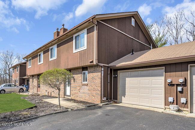view of property exterior with a chimney, aphalt driveway, brick siding, and a garage