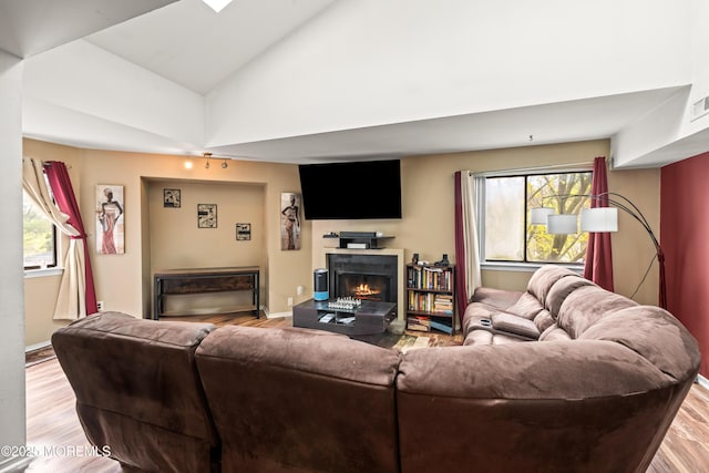 living area with visible vents, wood finished floors, a lit fireplace, and a healthy amount of sunlight
