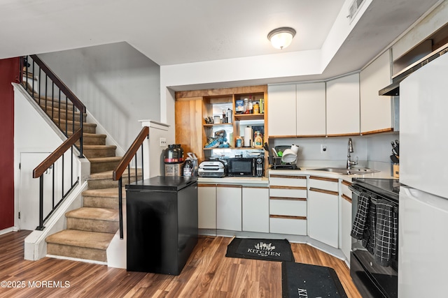 kitchen with open shelves, a sink, black appliances, light wood-type flooring, and white cabinetry