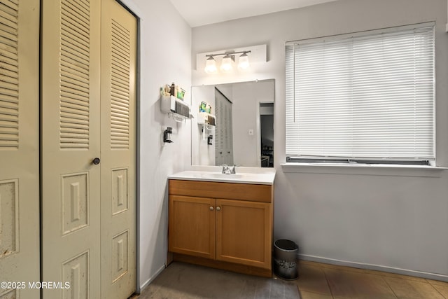 bathroom with baseboards, vanity, tile patterned flooring, and a closet