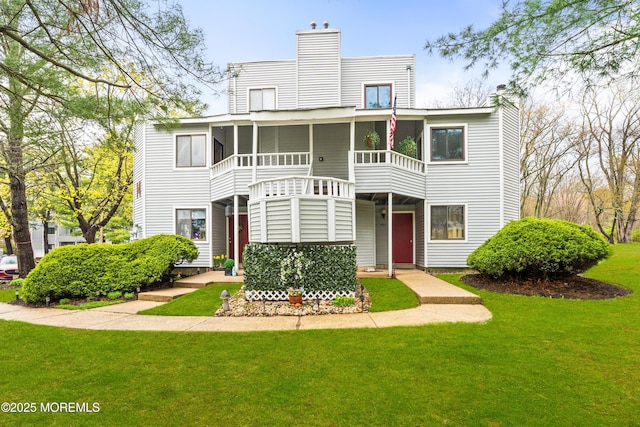 view of front of property featuring a chimney, a front lawn, and a sunroom