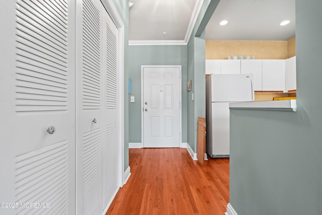 hall with light wood finished floors, baseboards, recessed lighting, and crown molding