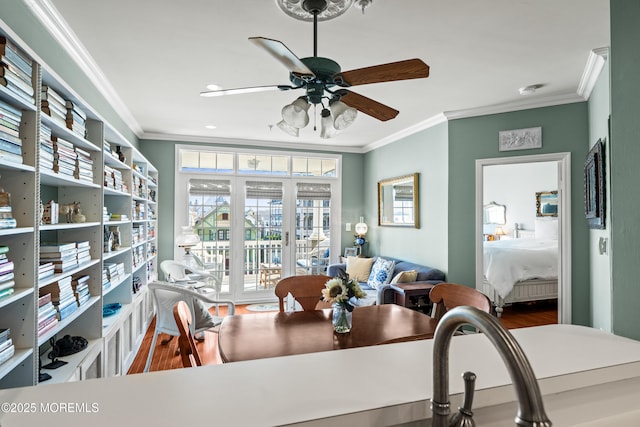 dining room featuring crown molding, wood finished floors, a ceiling fan, and plenty of natural light