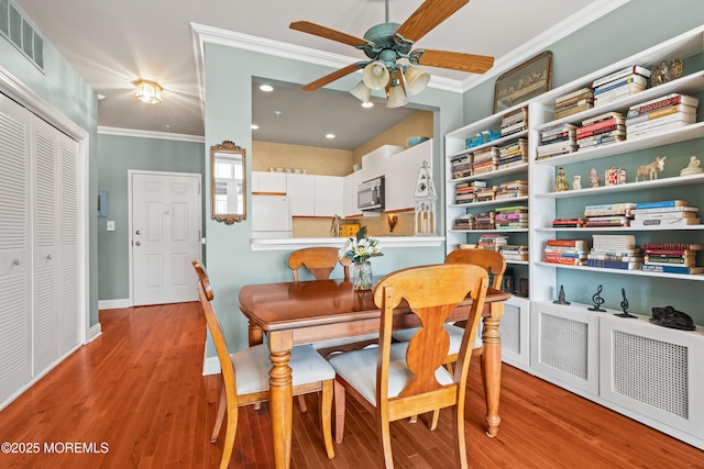 dining room with ornamental molding, wood finished floors, ceiling fan, recessed lighting, and baseboards