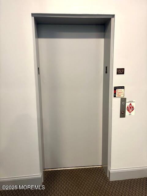 elevator with carpet flooring and baseboards