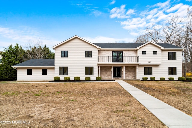 view of front of house featuring a balcony and a front yard