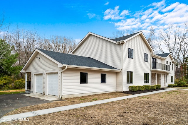 view of home's exterior featuring driveway, a balcony, a shingled roof, and a garage