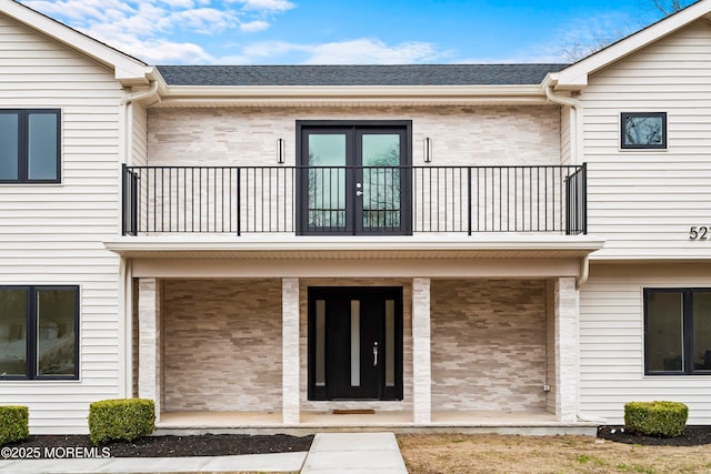 exterior space featuring brick siding, covered porch, and a balcony