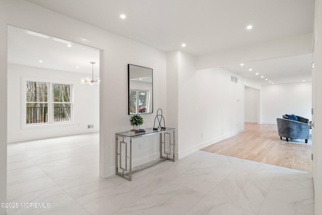 hall with recessed lighting, visible vents, baseboards, and an inviting chandelier