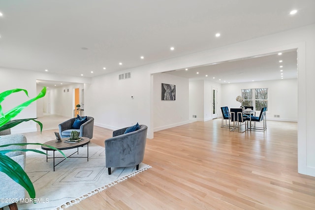 living room featuring light wood finished floors, baseboards, visible vents, and recessed lighting