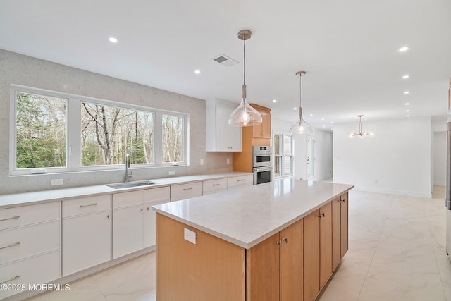 kitchen featuring a center island, a sink, double oven, marble finish floor, and recessed lighting