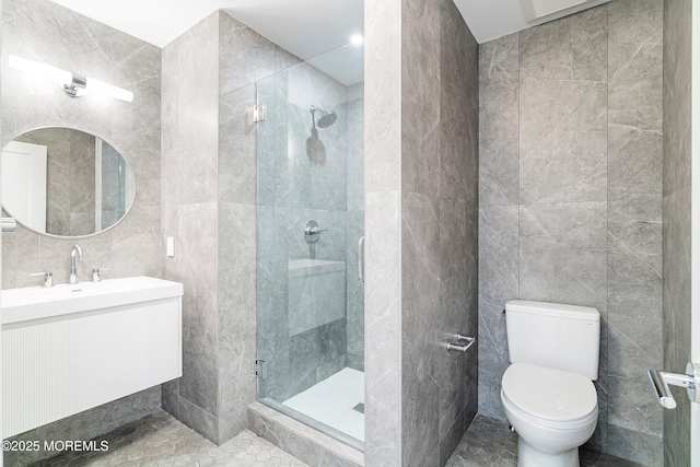 full bathroom with vanity, toilet, a stall shower, and tile walls