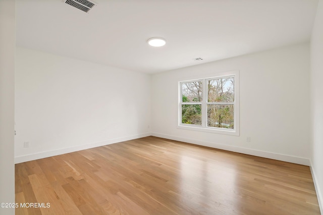 unfurnished room with light wood finished floors, baseboards, and visible vents
