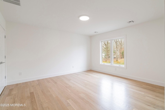 spare room with baseboards, visible vents, and light wood-style floors