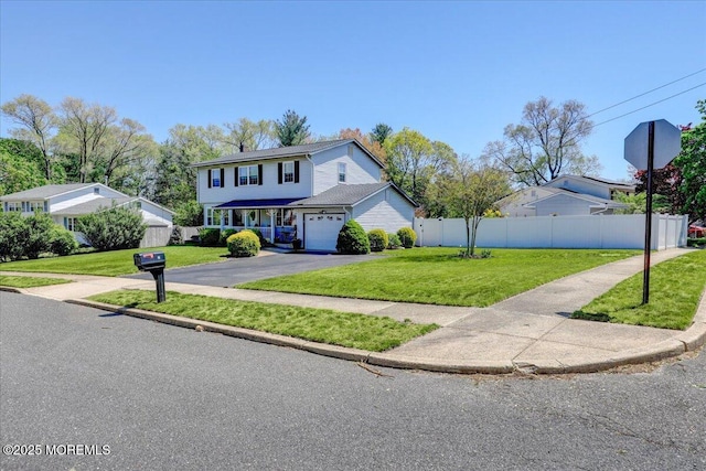 traditional home with fence, driveway, a front lawn, and a garage