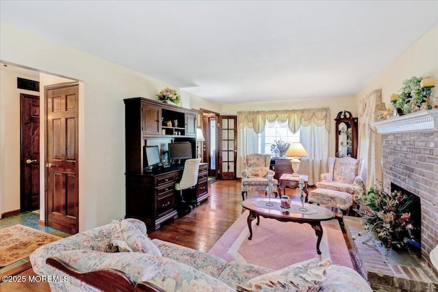 living room with dark wood-style flooring and a brick fireplace