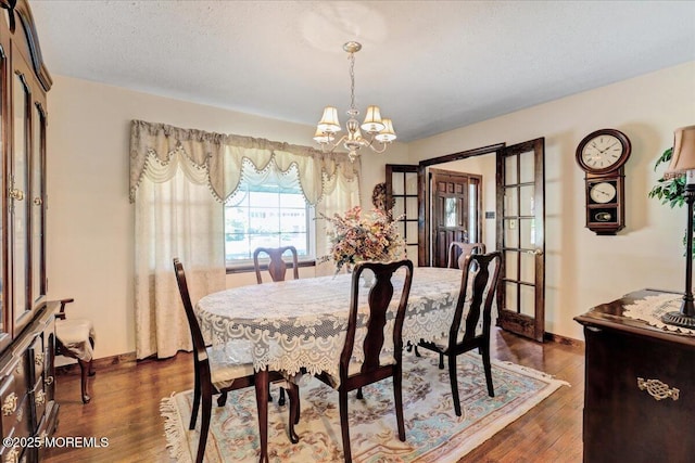 dining room with baseboards, a notable chandelier, dark wood-style floors, and french doors